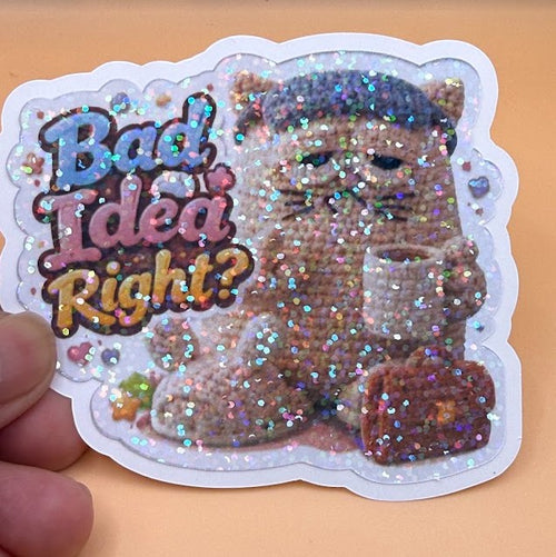 Todo Tumi holographic laminated sticker featuring a grumpy crochet cat with a coffee cup and briefcase.